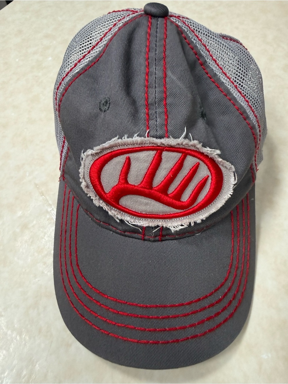Whitetail Properties trucker hat gray and red with a distress raw-edge patch